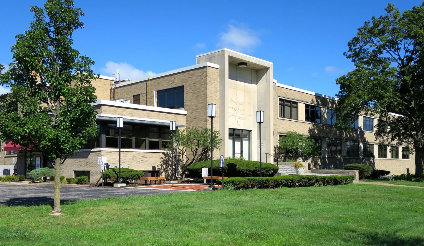 A mid-century building with a blue sky above and grass beneath.