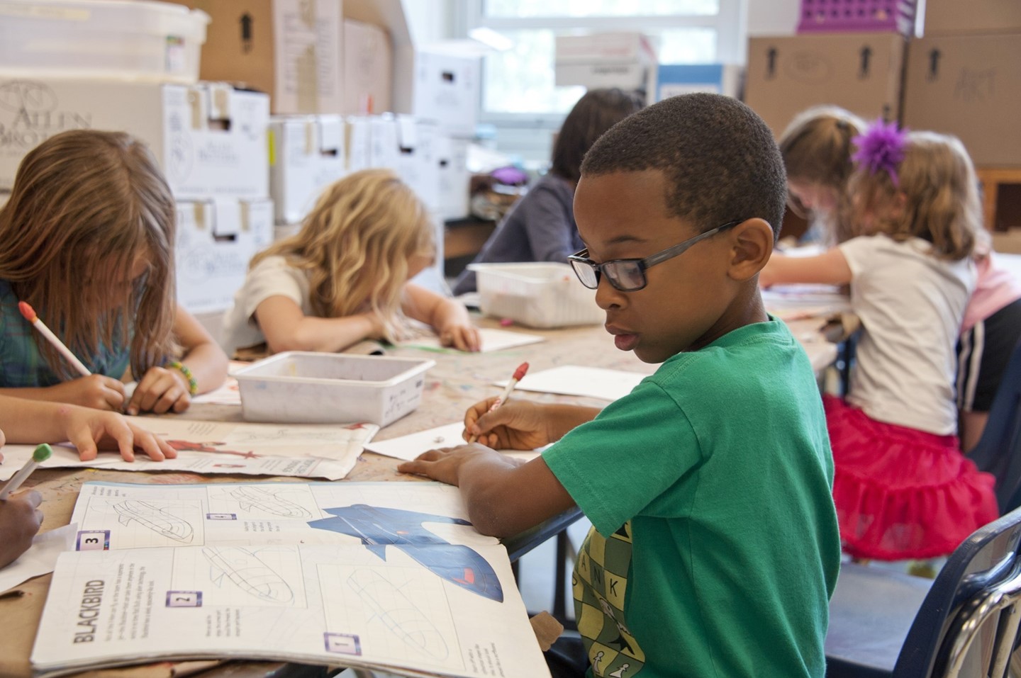 Elementary child working on a project with other children in the background.