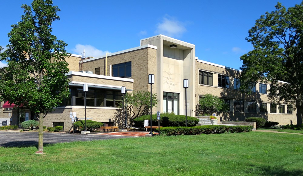 A photograph of a tan midcentury-style building on a sunny day.