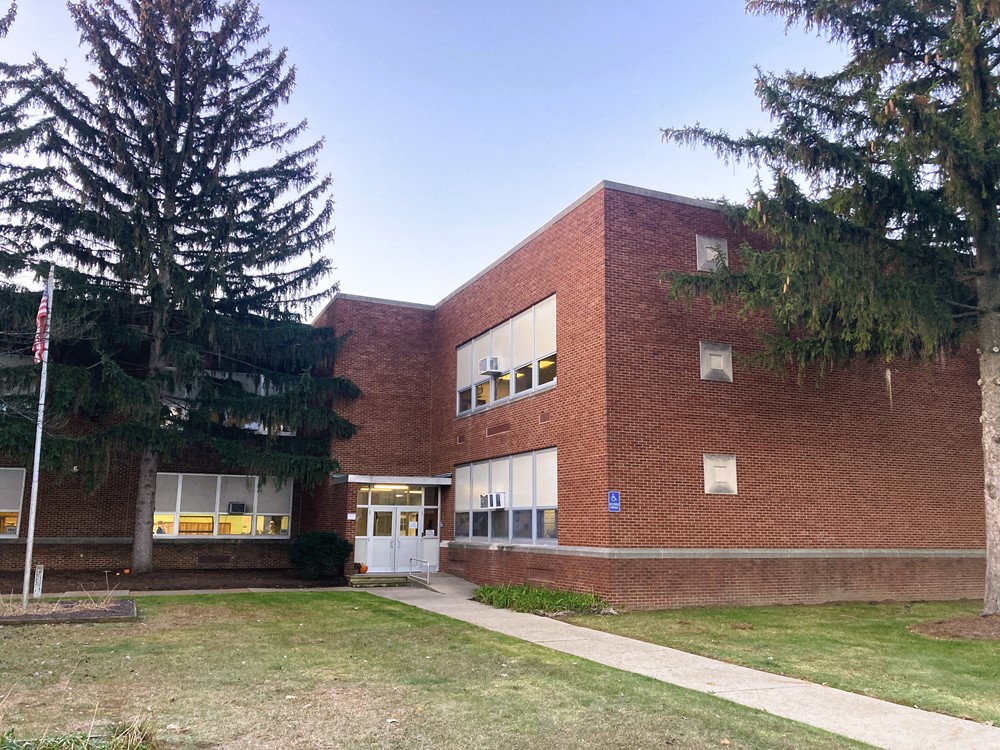 A red brick building with trees near the door.